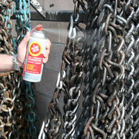 Man applying Fluid Film on chains